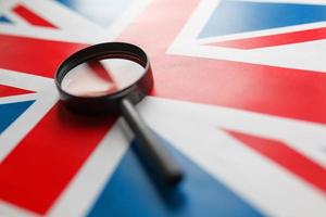 UK flag looking through a magnifying glass. Total surveillance of the country of England. The concept of hidden threats and control over the country photo