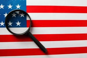 The US flag looks through a magnifying glass. Total surveillance of the United States. The concept of hidden threats and control over the country photo