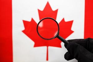 Canadian flag motrit through a magnifying glass. Total surveillance of the Canadian country. The concept of hidden threats and control over the country