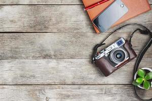 Classic camera with a brown organizer red pen on a gray wooden, vintage desk with a telephone and green growth. The concept of the list for the photographer in travels. Free space in country style photo