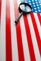 la bandera estadounidense mira a través de una lupa. vigilancia total de los estados unidos. el concepto de amenazas ocultas y control sobre el país foto