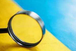 UKRAINE flag looking through a magnifying glass. The study of the history and culture of the people of the country of Ukraine. The concept of studying the geography, customs of Ukrainians photo