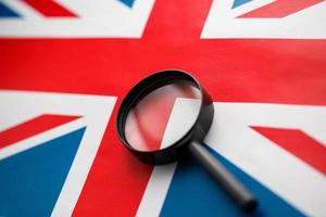 bandera del Reino Unido mirando a través de una lupa. vigilancia total del país de inglaterra. el concepto de amenazas ocultas y control sobre el país foto
