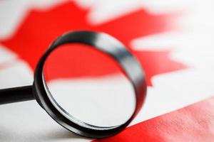 Canadian flag motrit through a magnifying glass. Total surveillance of the Canadian country. The concept of hidden threats and control over the country photo