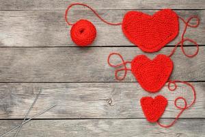 Three red knitted hearts on a gray wooden background, symbolizing love and family. Family relationship, bonds. photo