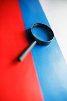 Flag of Russian Federation looking through a magnifying glass. Total surveillance of the country Russia. The concept of hidden threats and control over the country photo