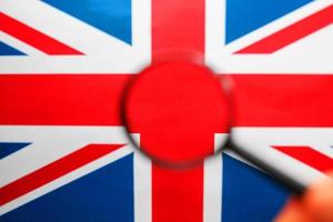 bandera del Reino Unido mirando a través de una lupa. vigilancia total del país de inglaterra. el concepto de amenazas ocultas y control sobre el país foto