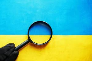 bandera de ucrania mirando a través de una lupa. el estudio de la historia y la cultura de la gente del país de ucrania. el concepto de estudiar la geografía, las costumbres de los ucranianos foto