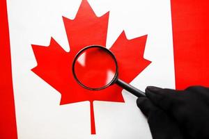 bandera canadiense mirando a través de una lupa. un estudio de la historia y la cultura de la gente de Canadá. el concepto de estudiar geografía, costumbres foto