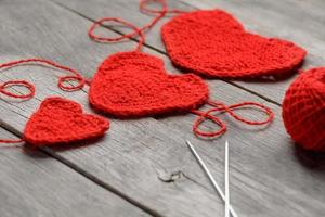 tres corazones de punto rojo sobre un fondo de madera gris, que simbolizan el amor y la familia. relación familiar, vínculos. foto