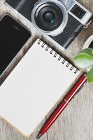 Classic camera with blank notepad page and red pen on gray wooden, vintage desk with telephone. photo