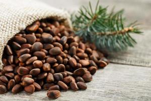 Pine nuts in a bag of burlap on an old vintage background with a fir green branch. In country style. photo