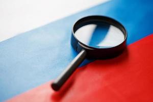 The flag of the Russian Federation looks through a magnifying glass. The study of the history and culture of the people of a large country of Russia. The concept of studying geography photo