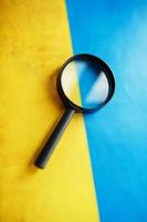 UKRAINE flag looks through a magnifying glass. Total surveillance of the country UKRAINE. The concept of hidden threats and control over the country photo