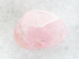 piedra de gema de cuarzo rosa caída sobre mármol blanco foto