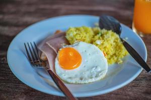cierre el desayuno en la mesa de madera. jamón de huevo cocido y arroz cocido el desayuno fácil por la mañana. foto