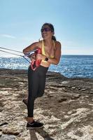 FITNESS LATIN WOMAN IN SPORTS SET TRAINING WITH ELASTIC BAND, WEIGHTS, GYM EXERCISES, IN FRONT OF THE WATER. photo