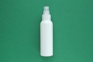 White unbranded plastic dispenser spray bottle on green background with copy space for text. Cosmetic package mockup, liquid soap flacon, hand sanitizer without label, shampoo organic spa, shower gel photo