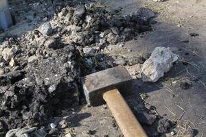 Close-up of big metal steel sledge hammer with wooden handle on cracking old pavement after road breaking. Hard work technical equipment on construction site. Industry tools. Work labor concept photo