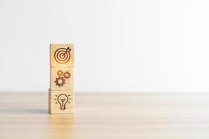 dartboard above Gear and Lightbulb icon block on desk. business planning process, goal, strategy, target, mission, action, objective, teamwork and idea concept photo