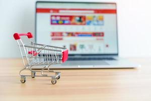 Shopping cart and laptop computer with marketplace website. business, technology, ecommerce, digital banking and online payment concept photo