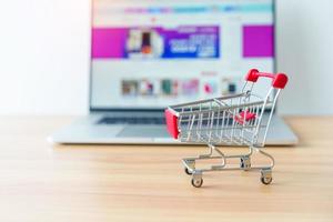 Shopping cart and laptop computer with marketplace website. business, technology, ecommerce, digital banking and online payment concept photo