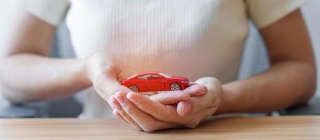 Hand holding Car toy. Vehicle insurance, warranty, Automobile rental, Transportation, Maintenance and repair concept. photo