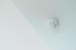 Smoke sensor detector mounted on roof in home or apartment. Safety and conflagration security concept photo