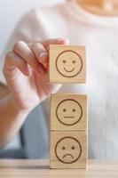 Hand choosing smile face from Emotion block for customer review, good experience, positive feedback, satisfaction, survey, evaluation, assessment, mood, world mental health day concept photo