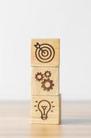 dartboard above Gear and Lightbulb icon block on desk. business planning process, goal, strategy, target, mission, action, objective, teamwork and idea concept photo