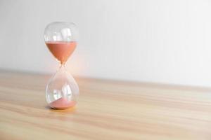 Hourglass on table, Sand flowing through the bulb of Sandglass measuring the passing time. countdown, patience, deadline, Life time and Retirement concept photo