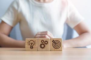 dartboard above Gear and Lightbulb icon block on desk. business planning process, goal, strategy, target, mission, action, objective, teamwork and idea concept photo