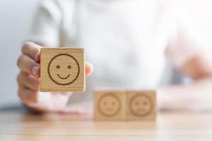 Hand choosing smile face from Emotion block.  customer review, good experience, positive feedback, satisfaction, survey, rating service, assessment, mood, world mental health day concept photo