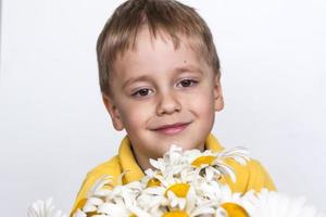 A cute boy with a beautiful bouquet of large daisies. Portrait of a child, funny and cute facial expression. Selective focus. photo