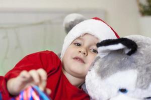 Portrait of a cute boy in a Santa Claus hat. Funny smiling child. Gifts, toys, joy, celebration. photo