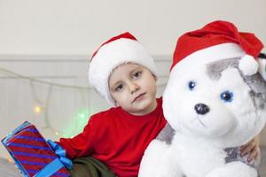 Portrait of a cute boy in a Santa Claus hat. Funny smiling child. Gifts, toys, joy, celebration. photo