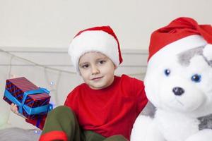 Portrait of a cute boy in a Santa Claus hat. Funny smiling child. Gifts, toys, joy, celebration. photo