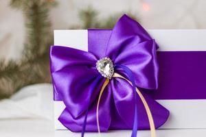 A Christmas gift decorated with a beautiful bow on a light background with a fir twig. Gifts, joy, surprise. Selective focus. the concept of Christmas and New Year. photo