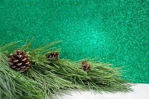 Natural pine tree Branches with cones on white table. Blurred green bokeh. Christmas, New Year. Copy space photo