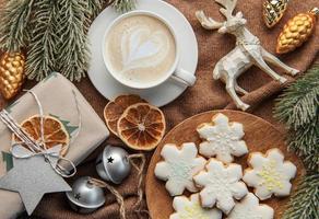 A cup of coffee latte, homemade cookies and Christmas balls and knitted sweater. photo