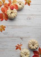 Autumn leaves and pumpkins over old wooden background photo