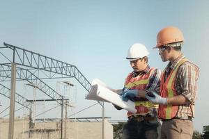 ingeniero estructural y trabajador que trabaja con planos discuten en el sitio de construcción al aire libre. foto