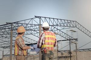 Engineer and worker watching blueprint on construction site photo