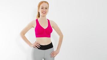 Young red haired girl in sport wear clothes isolated on white background. Slim body figure and healthy lifestyle. Fitness and sports concept. Banner photo