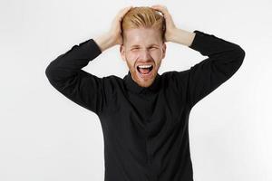 Man Depression signs and Symptoms. Young redheaded guy with red beard and black shirt shouting hard and angry. Failed startup and fail exam concept. Unhappy businessman with aggressive feelings. photo
