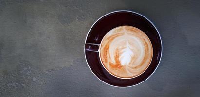 Top view of cup of art cappuccino or latte coffee on black or gray background or table at caf shop. Flat lay of hot drinking in glass with copy space. Food design concept. photo