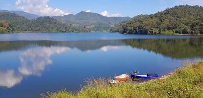 Landscape view of lake or river with boat, green mountain hill and blue sky background at Huai Bon reservoir Chiang Mai, Thailand. Park, Beauty of nature and Natural wallpaper. Landmark for travel. photo