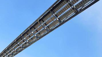 Bottom view of stainless steel electrical or communication cable tray with clear blue sky background. Iron bridge cross to air or heaven and industrial and installed system concept. photo