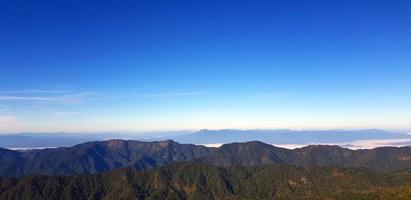 vista del paisaje de la colina de la montaña verde con niebla y fondo de cielo azul claro con espacio de copia arriba en el parque nacional doi pha hom pok, chiang mai, tailandia. papel tapiz natural y belleza de la naturaleza. foto
