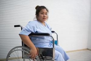 Asian fat woman patient sitting on a wheelchair, knee pain, excessive weight , health care concept. photo